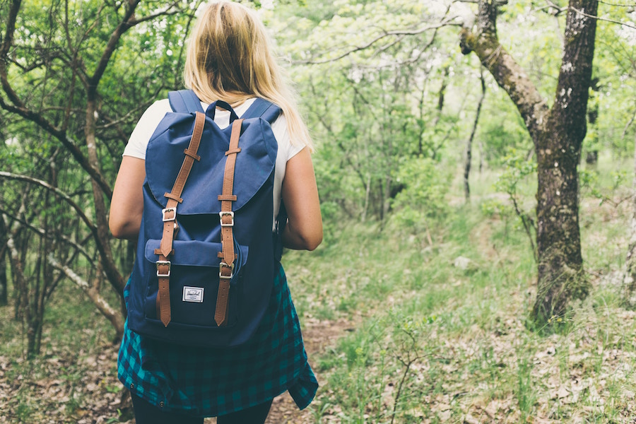 Back of schoolgirl walking in woods. Image via Unsplash.